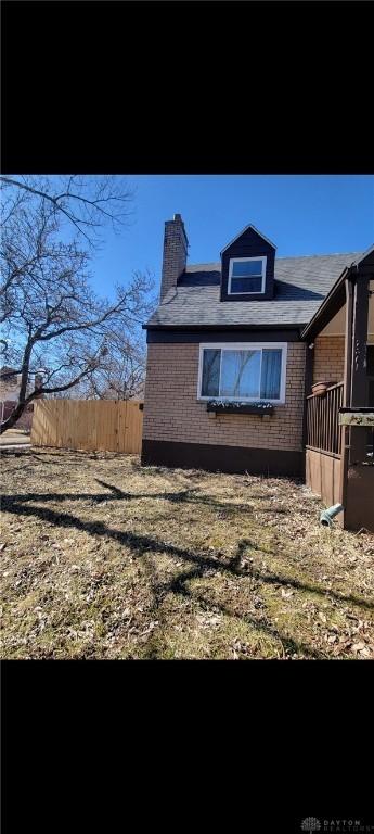 view of side of home featuring fence and brick siding