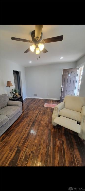 living area featuring visible vents, wood-type flooring, baseboards, and ceiling fan