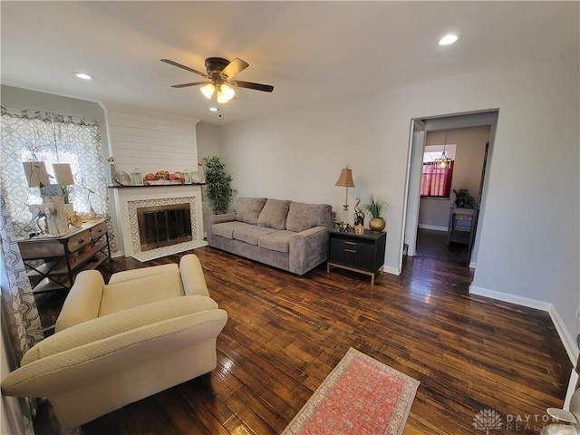 living room with recessed lighting, a fireplace with flush hearth, wood finished floors, and baseboards