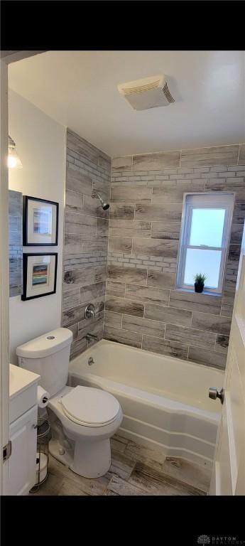 full bathroom featuring visible vents, toilet, wood finished floors, washtub / shower combination, and vanity