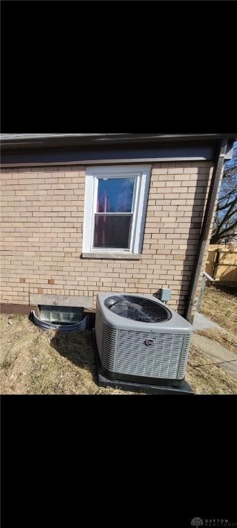 exterior details featuring brick siding and central AC