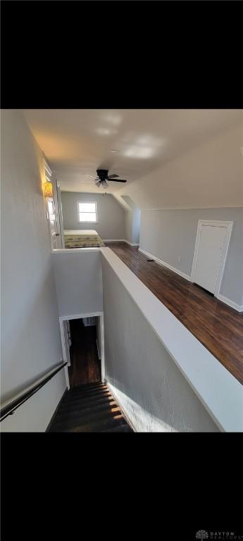 stairs with wood finished floors, a ceiling fan, and vaulted ceiling