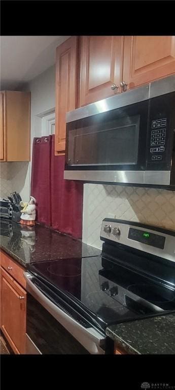 kitchen featuring backsplash, appliances with stainless steel finishes, and dark stone countertops