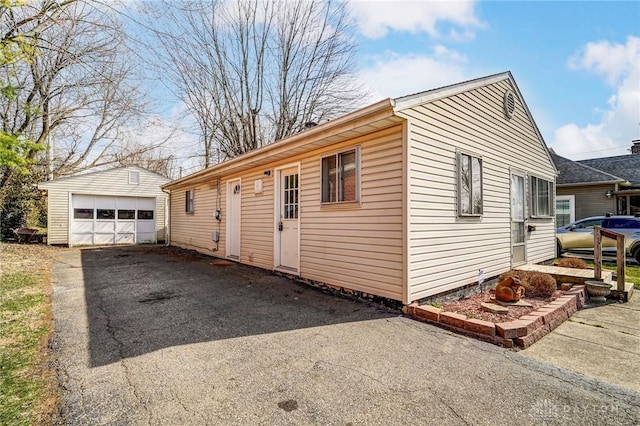 view of property exterior with a garage, an outbuilding, and driveway