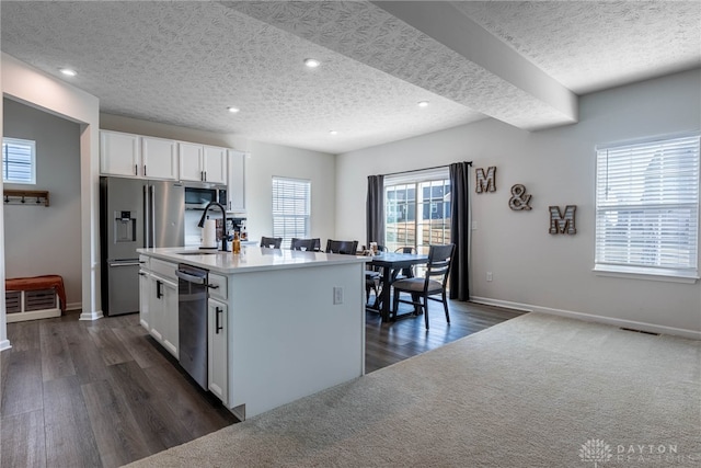 kitchen with visible vents, a kitchen island with sink, stainless steel appliances, a sink, and white cabinetry