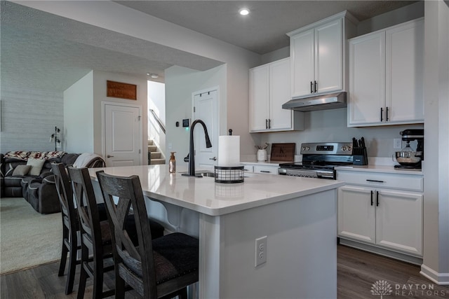 kitchen with a center island with sink, stainless steel range with electric stovetop, under cabinet range hood, white cabinetry, and open floor plan