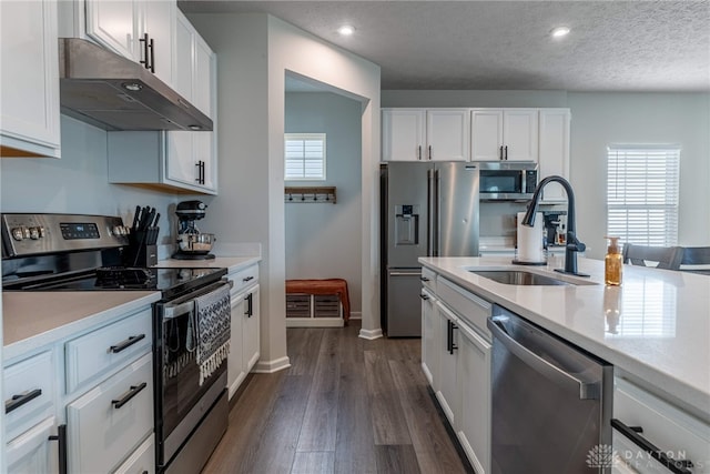 kitchen featuring a sink, light countertops, white cabinets, under cabinet range hood, and appliances with stainless steel finishes