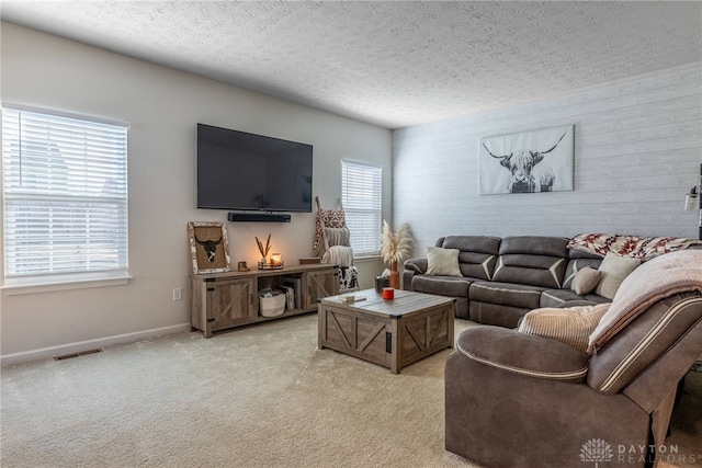 living area featuring visible vents, light carpet, a textured ceiling, and baseboards