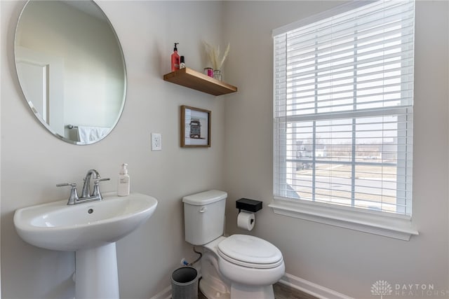 bathroom featuring a sink, baseboards, plenty of natural light, and toilet