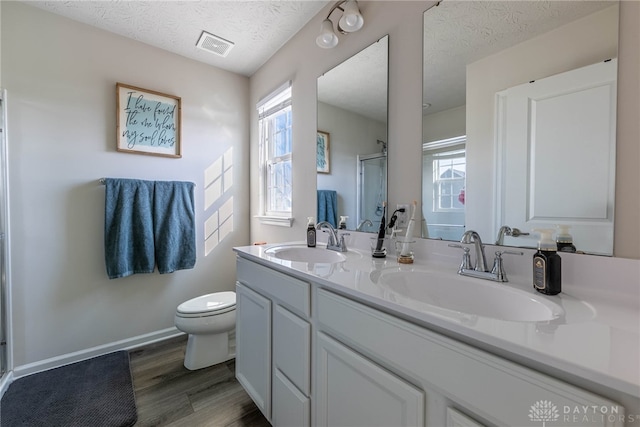 bathroom featuring a stall shower, a textured ceiling, and a sink