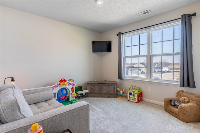 playroom featuring baseboards, carpet, visible vents, and a textured ceiling