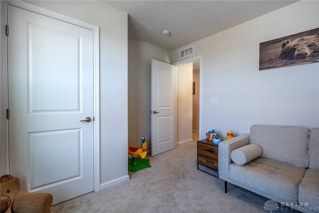 sitting room featuring visible vents, carpet floors, a textured ceiling, and baseboards