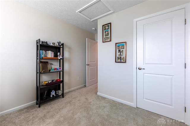 bedroom featuring baseboards, light colored carpet, attic access, and a textured ceiling