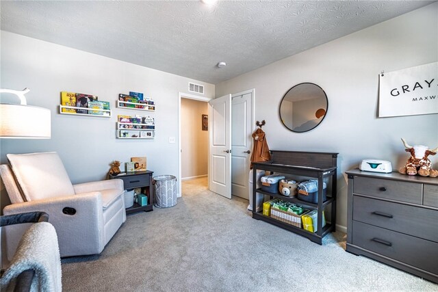 sitting room with visible vents, carpet floors, a textured ceiling, and baseboards