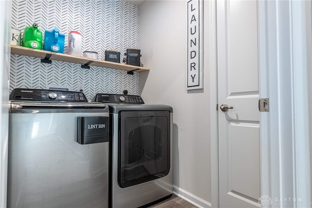 clothes washing area featuring baseboards, wood finished floors, laundry area, and washing machine and clothes dryer