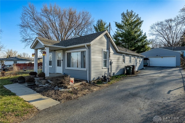 view of front of house featuring an outbuilding, fence, a garage, and a shingled roof