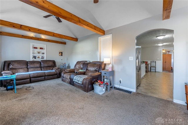 carpeted living area featuring baseboards, arched walkways, a ceiling fan, and vaulted ceiling with beams