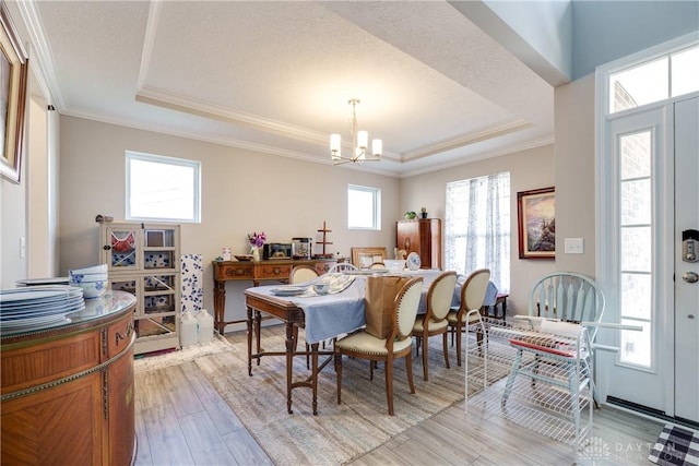 dining area featuring a chandelier, light wood finished floors, a tray ceiling, and ornamental molding