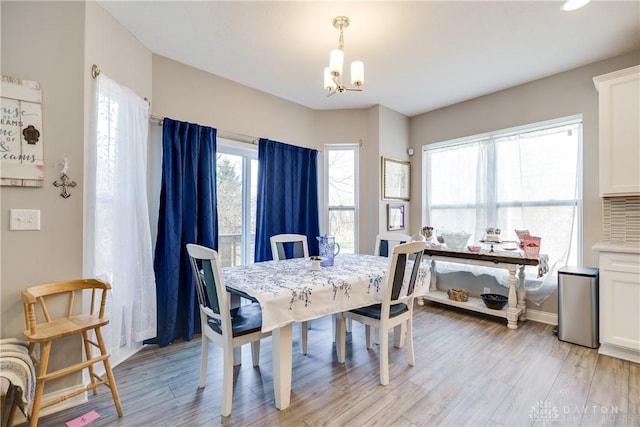 dining space with light wood-style floors, baseboards, and a chandelier