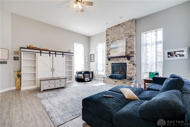 living area with a barn door, baseboards, wood finished floors, and a fireplace