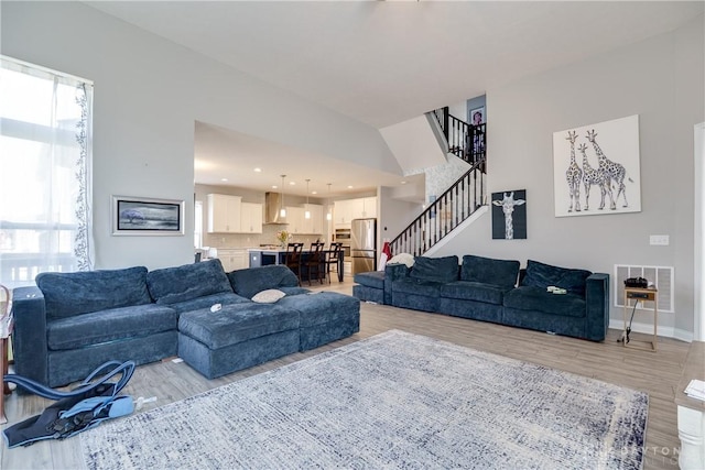 living area with recessed lighting, stairway, baseboards, and light wood-style flooring