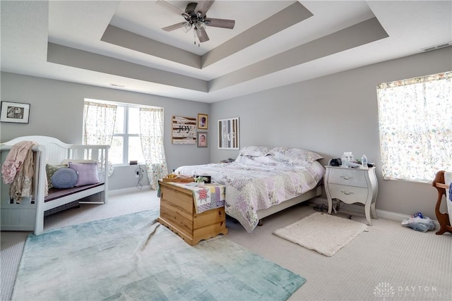 bedroom with a tray ceiling, visible vents, and carpet flooring