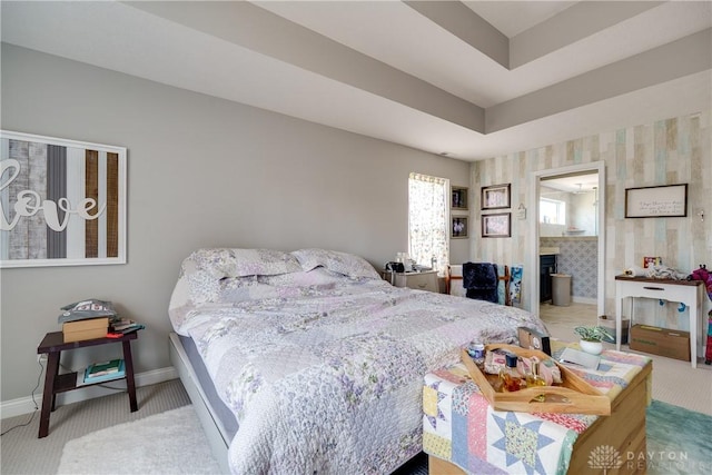 carpeted bedroom featuring wallpapered walls, baseboards, a fireplace, ensuite bathroom, and a raised ceiling