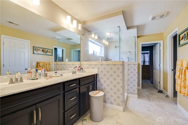 bathroom with a sink, visible vents, double vanity, and a shower stall