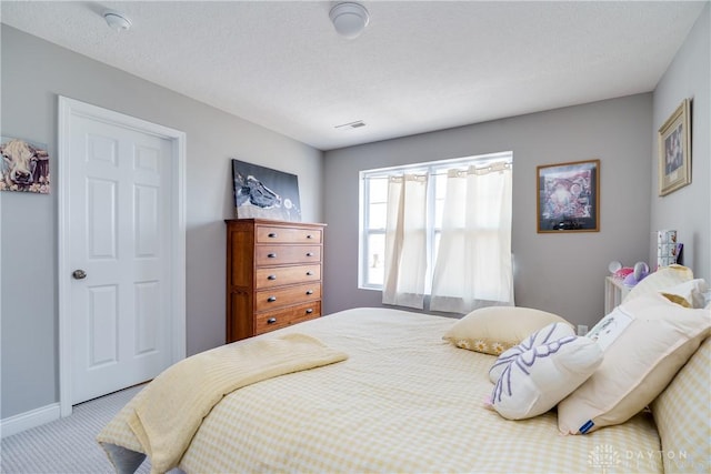 carpeted bedroom featuring visible vents, baseboards, and a textured ceiling