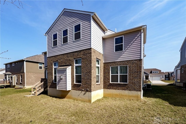 back of house featuring brick siding, entry steps, and a yard