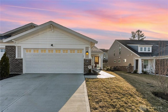 view of front of home featuring an attached garage, a lawn, brick siding, and driveway