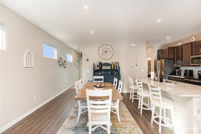 dining room with dark wood finished floors, recessed lighting, and baseboards