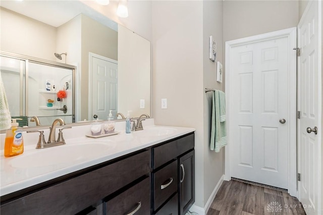 full bathroom featuring double vanity, a stall shower, wood finished floors, and a sink