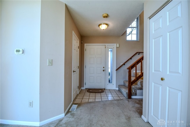 tiled foyer with stairway, carpet flooring, baseboards, and visible vents