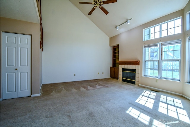 unfurnished living room with a fireplace, a healthy amount of sunlight, carpet floors, and high vaulted ceiling