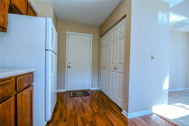 kitchen featuring brown cabinets, freestanding refrigerator, baseboards, and dark wood-style flooring