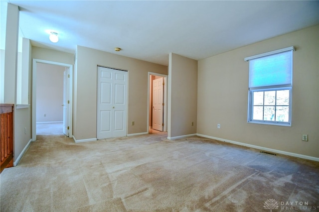 unfurnished bedroom featuring a closet, carpet floors, baseboards, and visible vents