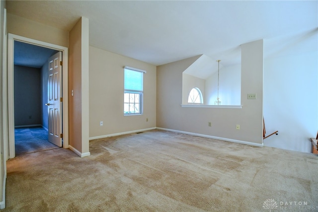 spare room featuring carpet flooring, baseboards, and vaulted ceiling