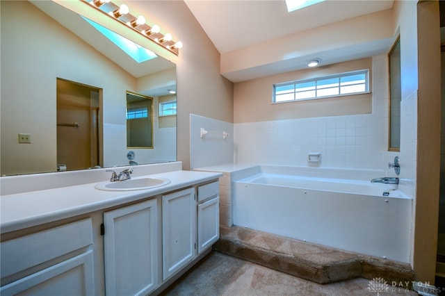 full bathroom featuring vaulted ceiling with skylight, vanity, and a garden tub