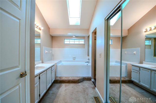 bathroom with visible vents, a skylight, two vanities, a sink, and a bath