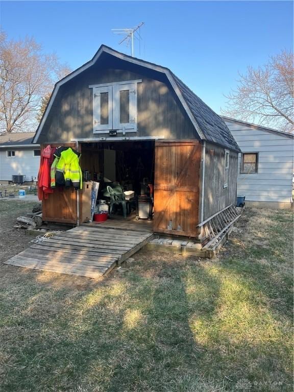 back of house with a gambrel roof, central AC unit, and an outdoor structure