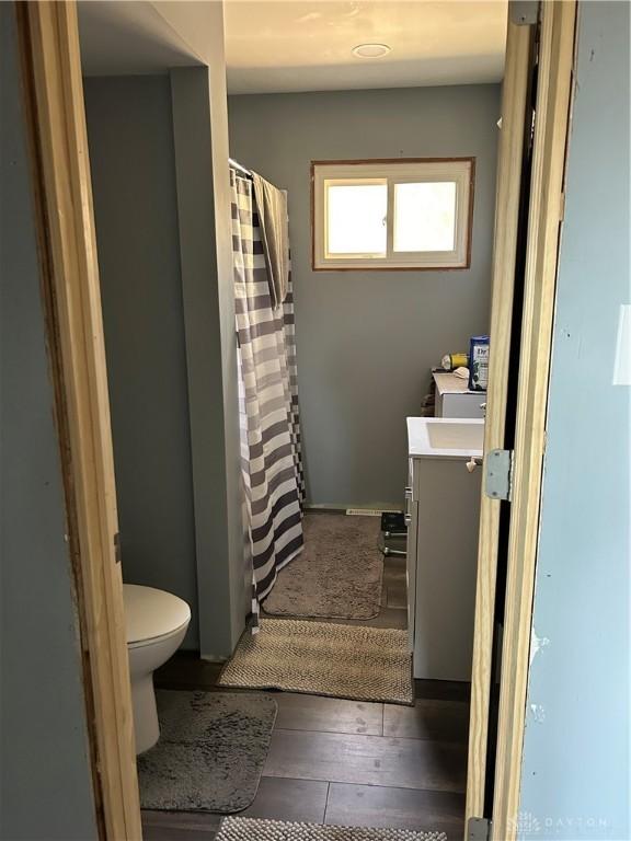 bathroom with toilet, vanity, a shower with curtain, and wood-type flooring