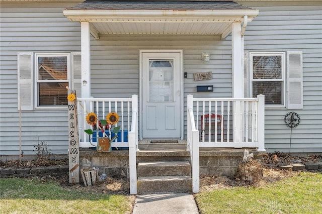 property entrance featuring covered porch and a shingled roof