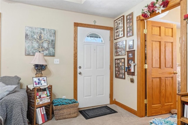 foyer featuring light colored carpet and baseboards