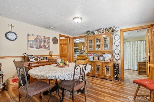 dining room featuring light wood finished floors, visible vents, and a textured ceiling