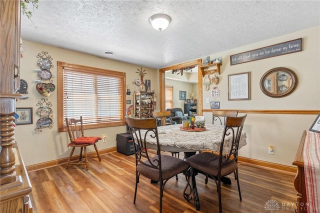 dining room with light wood-style flooring, visible vents, baseboards, and a textured ceiling