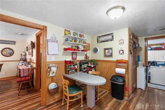 dining space with a wainscoted wall, visible vents, a textured ceiling, wood finished floors, and washer / dryer