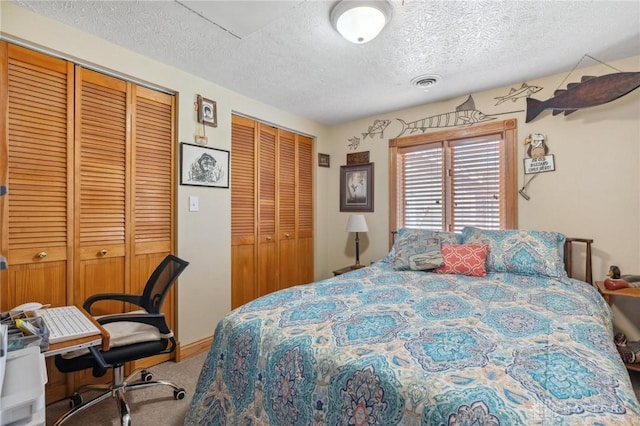 carpeted bedroom with visible vents, a textured ceiling, and two closets