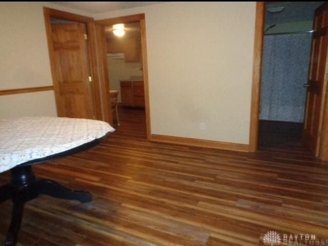 bedroom featuring a walk in closet, baseboards, ensuite bathroom, and dark wood-style flooring