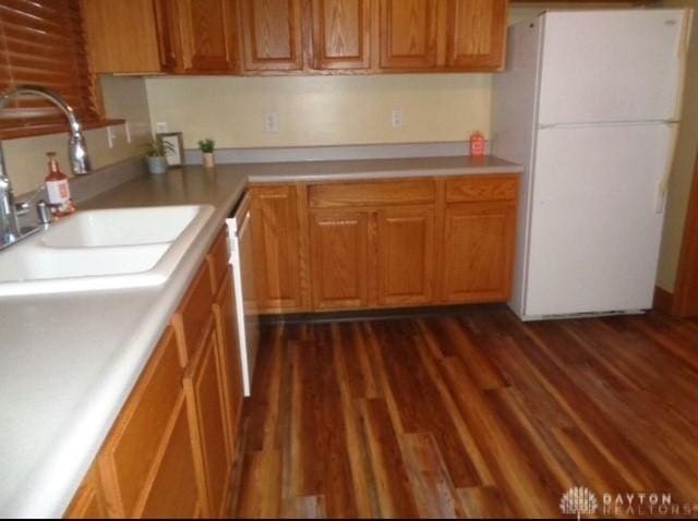 kitchen with a sink, dark wood-type flooring, light countertops, and freestanding refrigerator